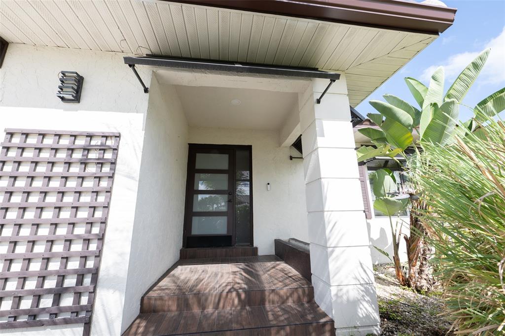 A front entryway features a dark wood door with glass panels and tiled steps — 376 PORTOFINO DRIVE, PUNTA GORDA, FL