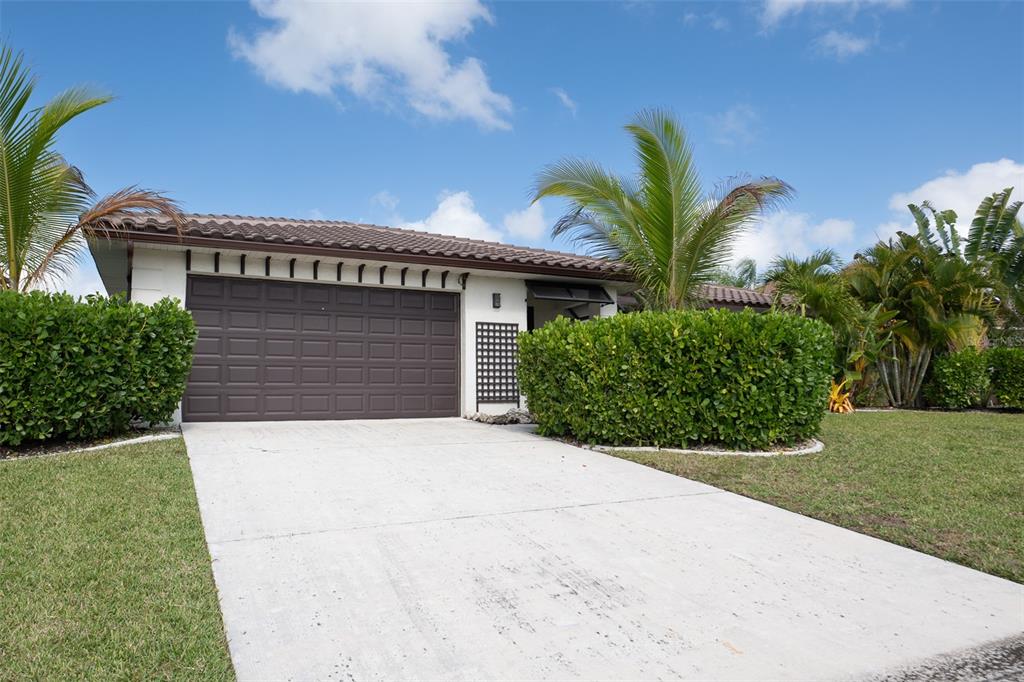 A single-story house with a brown garage door, concrete driveway, and surrounding tropical landscaping — 376 PORTOFINO DRIVE, PUNTA GORDA, FL