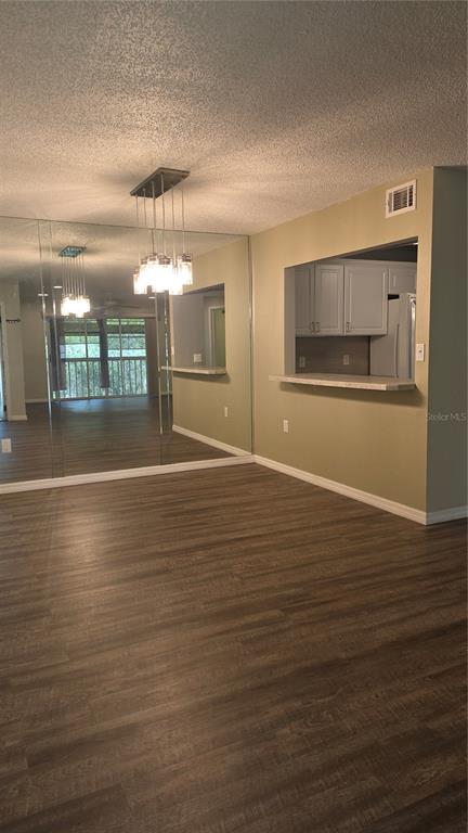A dining area with wood-look flooring, a mirrored wall, and a pass-through to the kitchen — 12119 SUNNY GLEN LANE UNIT E2, HUDSON, FL