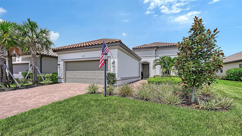 A single-story house with a two-car garage and a paved driveway at sunset — 3022 VITTORIO COURT, BRADENTON, FL