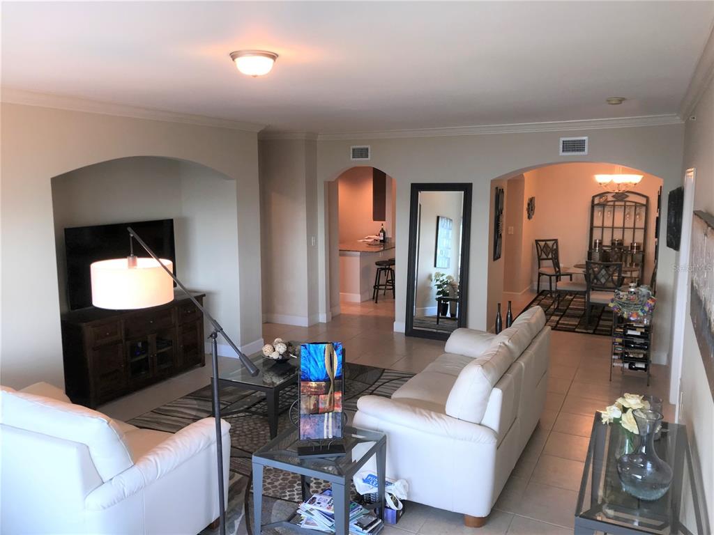 A living room with white leather sofas, a television alcove, and an adjacent dining area — 808 3RD AVENUE W UNIT 509, BRADENTON, FL