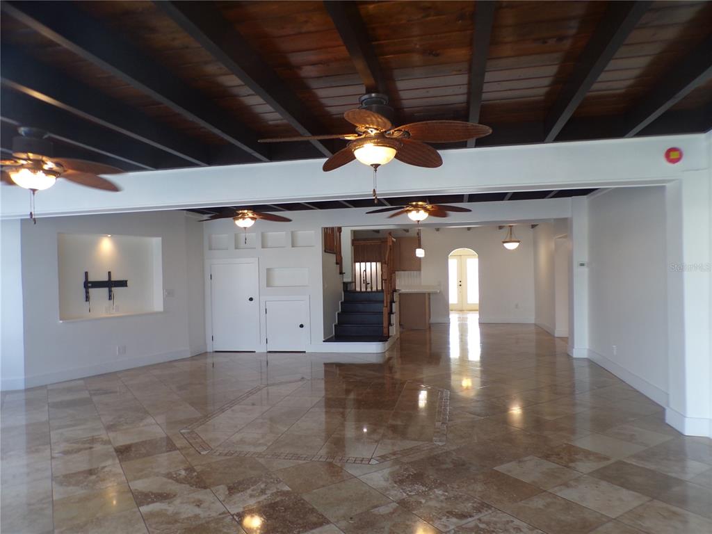 A spacious room features a wood-paneled ceiling with exposed beams, ceiling fans, and tiled floors — 179 MARIA COURT, PUNTA GORDA, FL