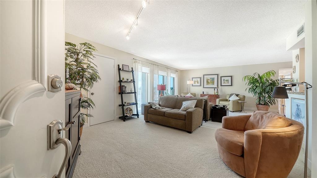 A view from a doorway into a carpeted living room with a sofa and armchair — 2301 GULF OF MEXICO DRIVE UNIT 44N, LONGBOAT KEY, FL
