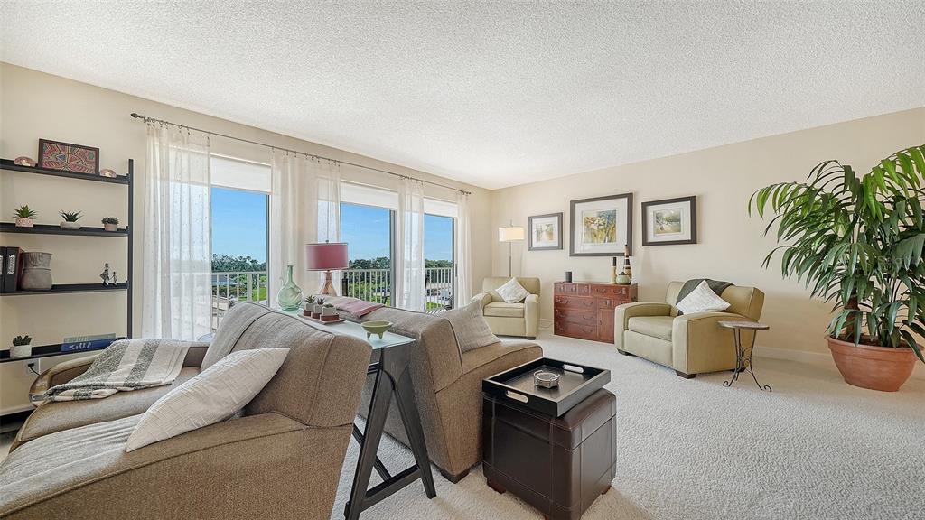 A living room features beige carpet, two sofas, two armchairs, and a large potted plant — 2301 GULF OF MEXICO DRIVE UNIT 44N, LONGBOAT KEY, FL
