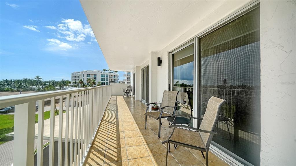 A balcony with tiled flooring, two chairs, and a metal railing overlooking a parking area — 2301 GULF OF MEXICO DRIVE UNIT 44N, LONGBOAT KEY, FL