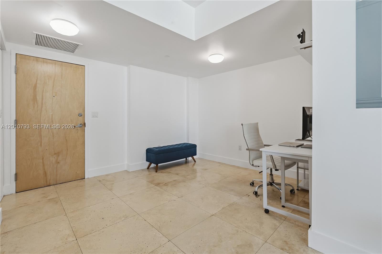 A home office features white walls, tile flooring, a wooden door, and a desk — 350 S Miami Ave # 3307, Miami FL 33130, MIAMI, FL