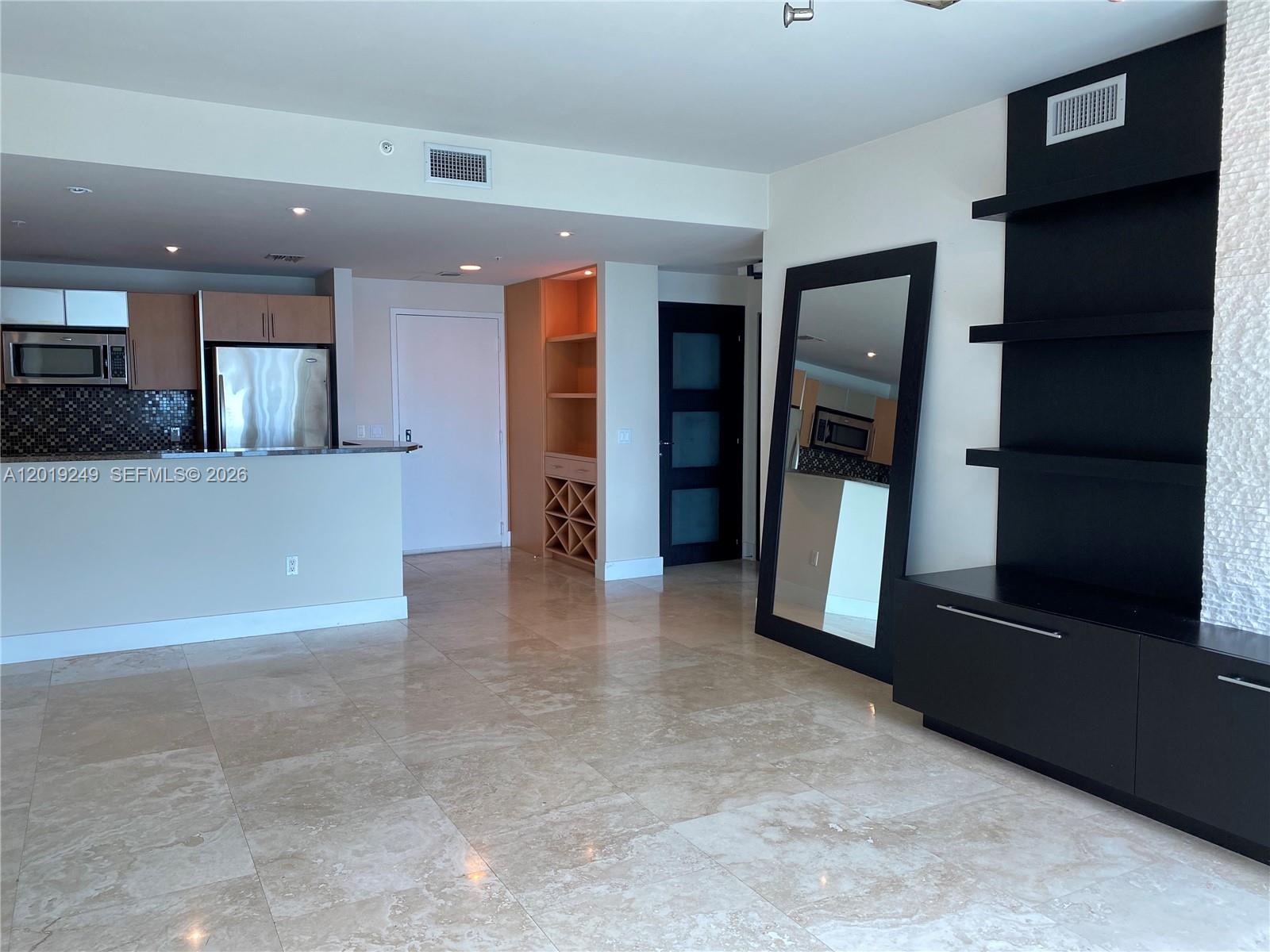 This living area features tile flooring, a kitchen with stainless appliances, and built-in shelving — 300 S Biscayne Blvd # 2606, Miami FL 33131, MIAMI, FL