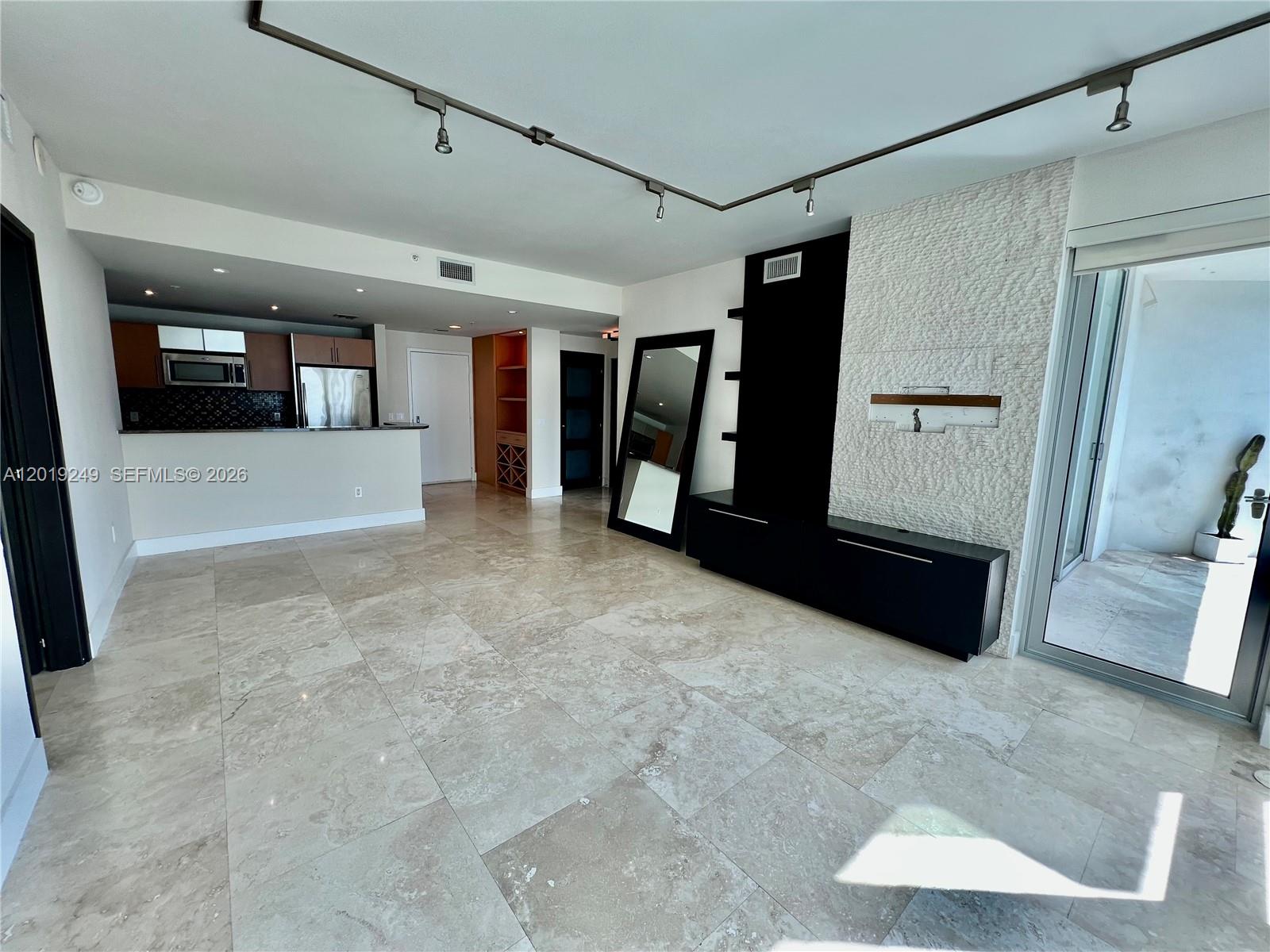 This living room features large stone floor tiles, a textured stone accent wall, and track lighting — 300 S Biscayne Blvd # 2606, Miami FL 33131, MIAMI, FL