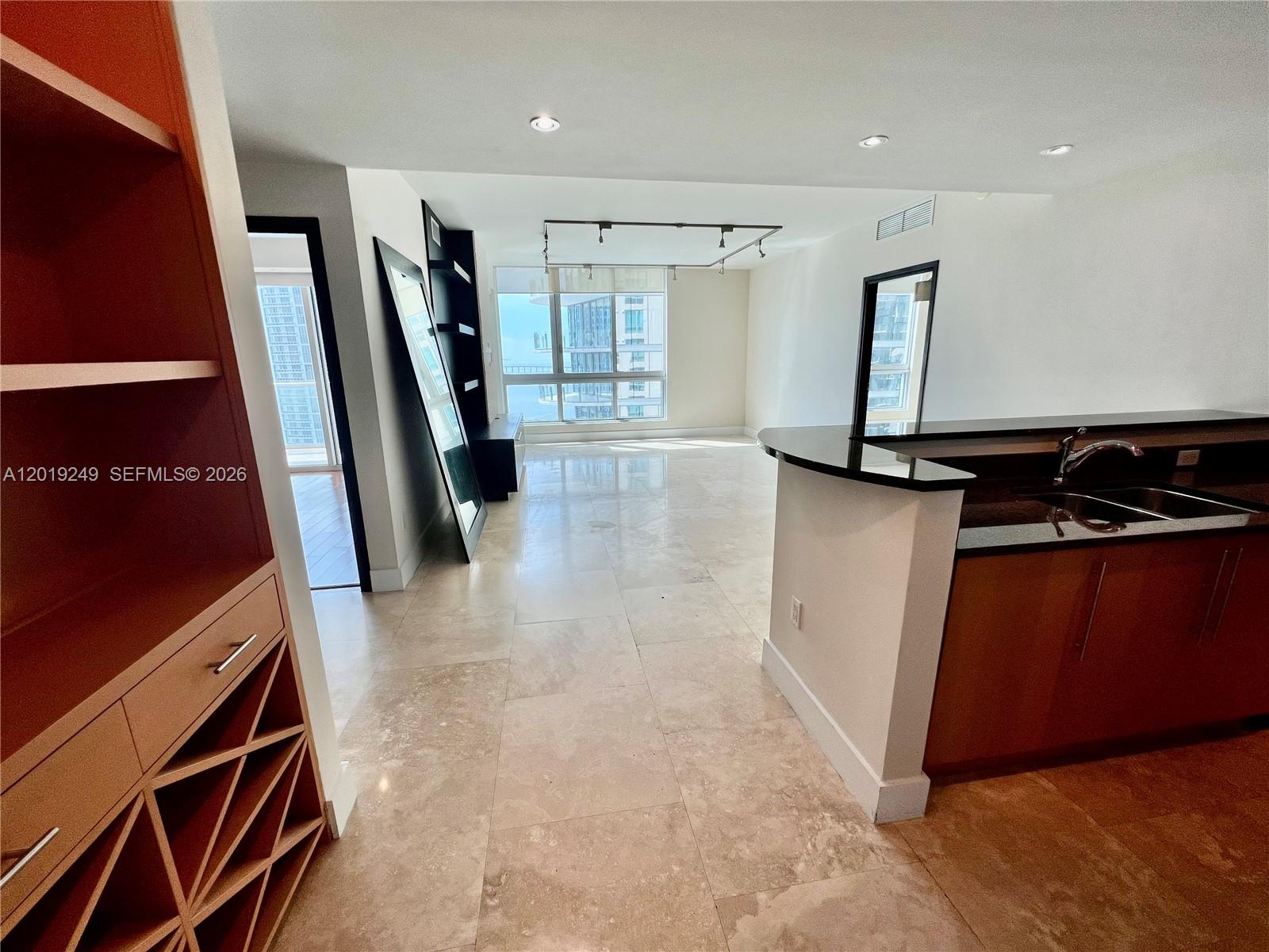 An open-concept living area features light tile flooring, a kitchen island, and floor-to-ceiling windows — 300 S Biscayne Blvd # 2606, Miami FL 33131, MIAMI, FL