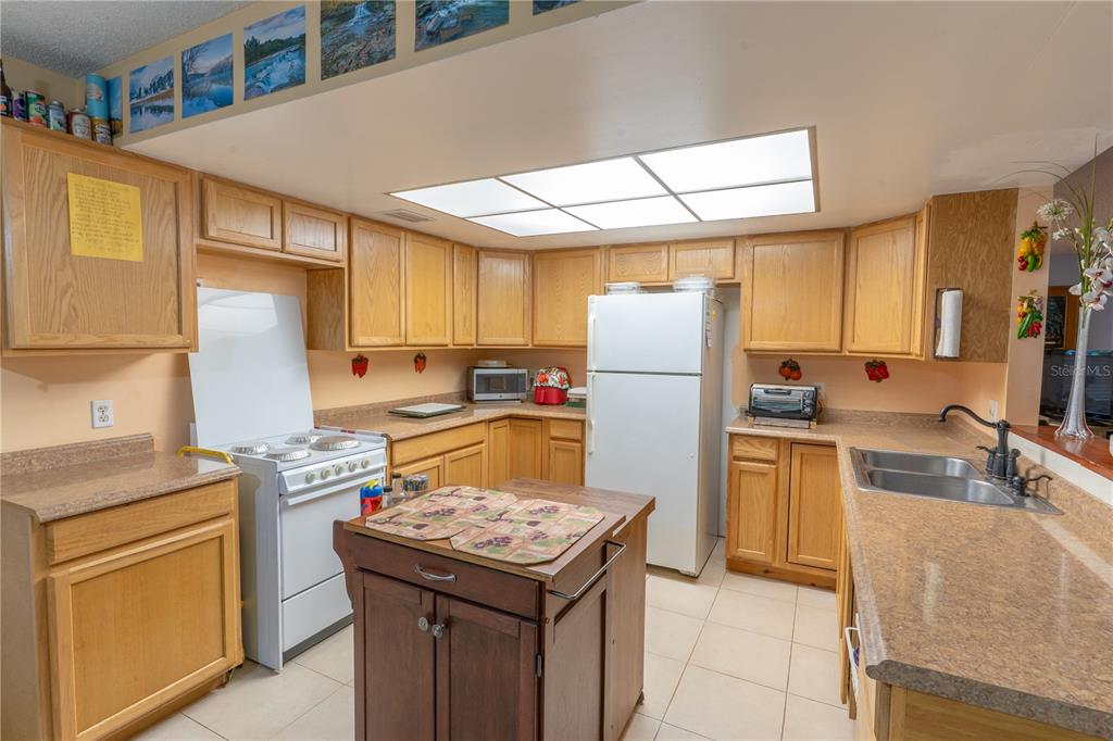 A kitchen with light wood cabinets, a white stove, a refrigerator, and a central island — 1329 HERNDON AVENUE, DELTONA, FL