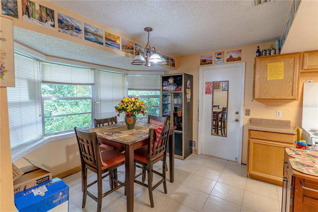 A dining area features a wooden table, four chairs, a bay window, and light-colored tile flooring — 1329 HERNDON AVENUE, DELTONA, FL
