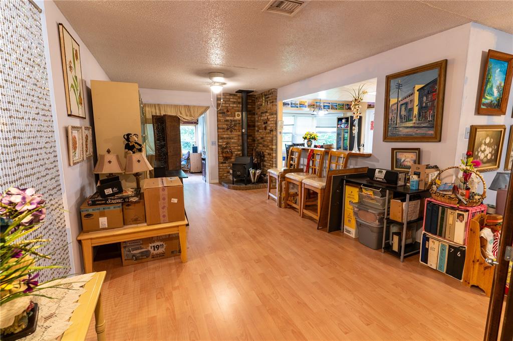 A living area with wood-look flooring, a brick fireplace, and an open kitchen counter — 1329 HERNDON AVENUE, DELTONA, FL