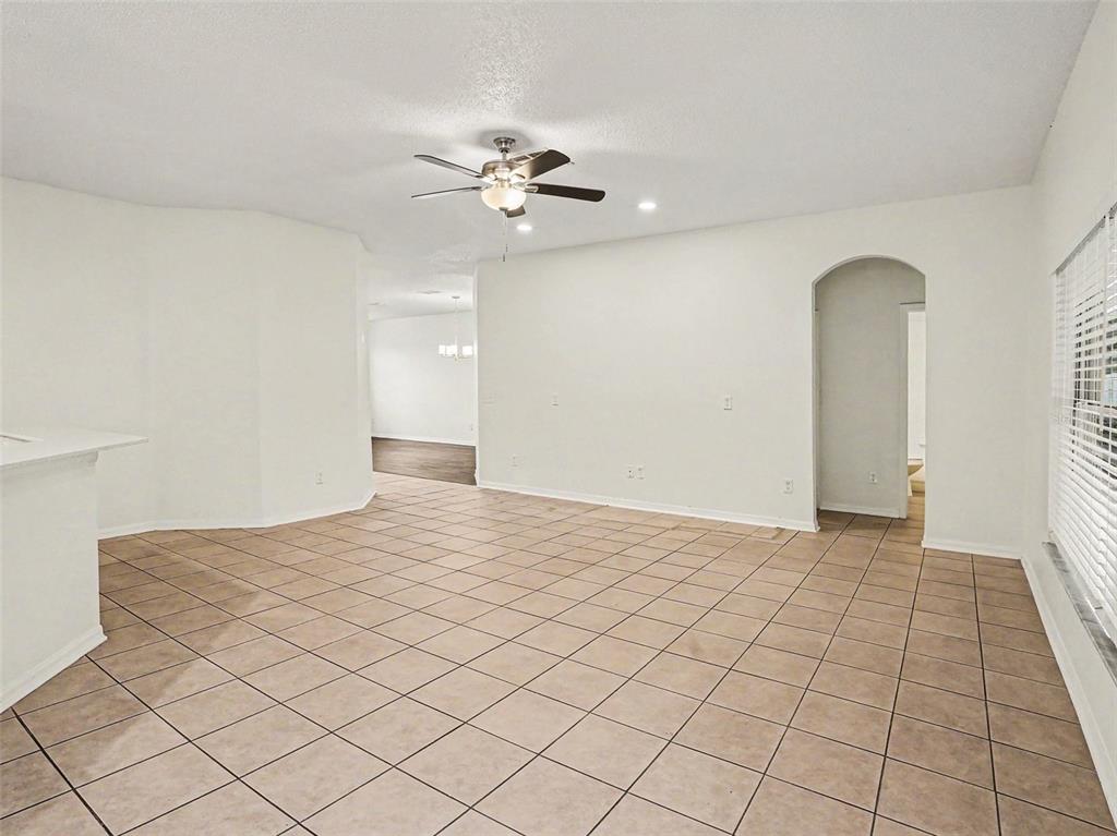 A spacious room with light-colored tile flooring, white walls, and a ceiling fan — 8857 PALISADES BEACH AVENUE, ORLANDO, FL