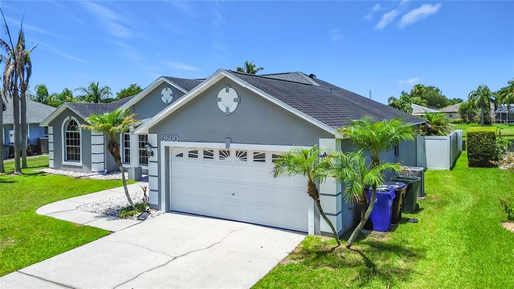 A gray single-story house with a white garage door and a dark shingled roof — 3600 YELLOW BIRD COURT, ST CLOUD, FL