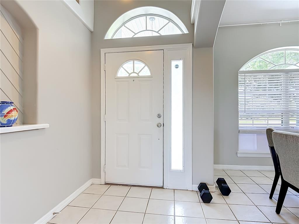 An entryway features a white front door with a sidelight, arched windows, and tiled flooring — 3600 YELLOW BIRD COURT, ST CLOUD, FL