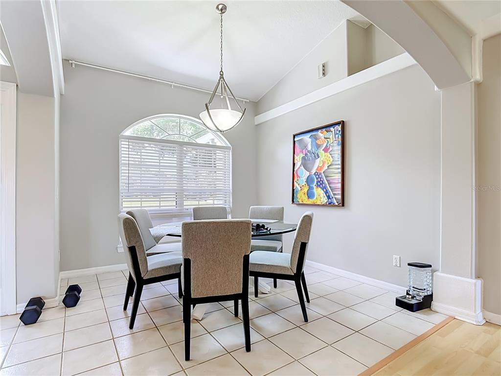 A dining area features a glass-topped table, upholstered chairs, a pendant light, and tile flooring — 3600 YELLOW BIRD COURT, ST CLOUD, FL