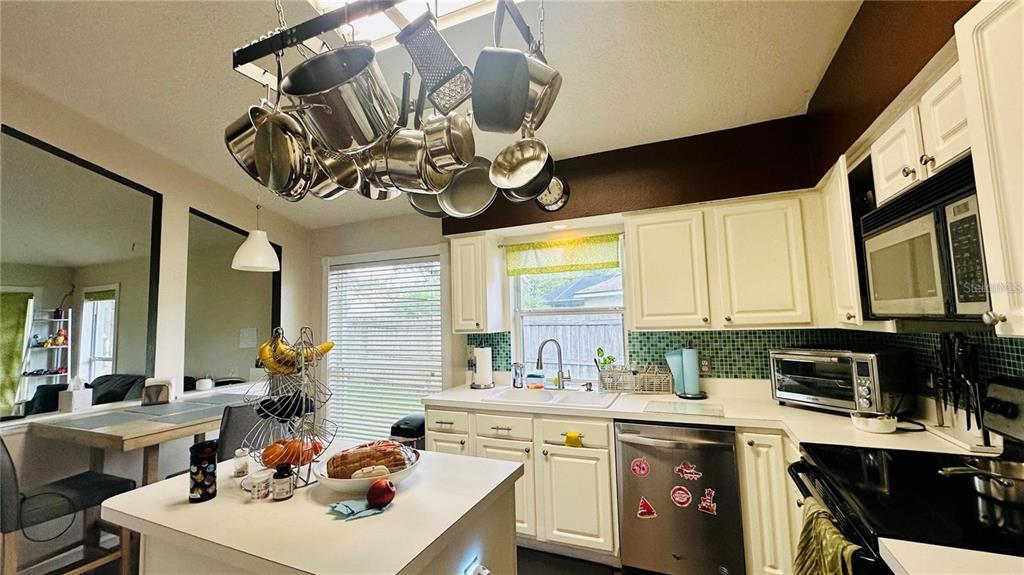 A kitchen features white cabinetry, a central island, a hanging pot rack, and green tile — 3227 HERONS POINT CIRCLE, KISSIMMEE, FL