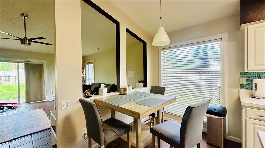 A dining area features a wooden table, grey chairs, large wall mirrors, and a window — 3227 HERONS POINT CIRCLE, KISSIMMEE, FL