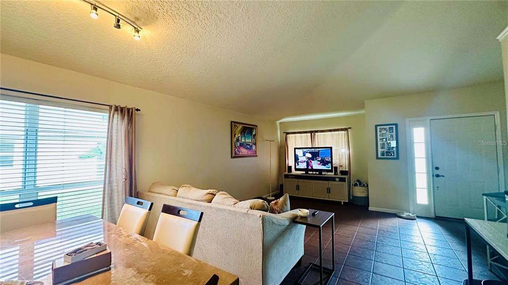 A living room with a sofa, dining table, television, and tile flooring — 3227 HERONS POINT CIRCLE, KISSIMMEE, FL