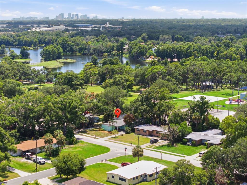 An aerial view shows a residential neighborhood with a lake and a city skyline — 609 W RIVER DRIVE, TAMPA, FL