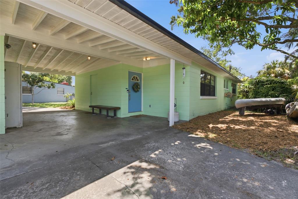 A light green house features a concrete carport, a blue front door, and a driveway — 609 W RIVER DRIVE, TAMPA, FL