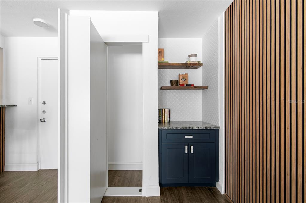 A hallway features a dark blue cabinet, open wood shelving, and a vertical wood slat wall — 2302 S MANHATTAN AVENUE UNIT 108, TAMPA, FL
