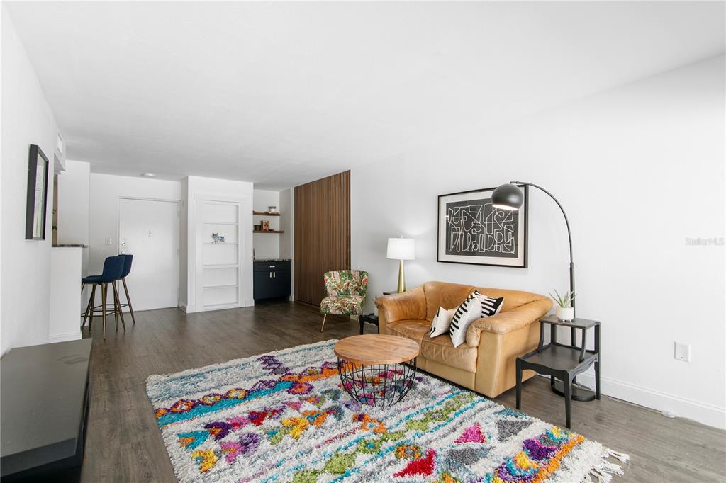 A living room features a colorful rug, tan leather sofa, and a small wet bar area — 2302 S MANHATTAN AVENUE UNIT 108, TAMPA, FL
