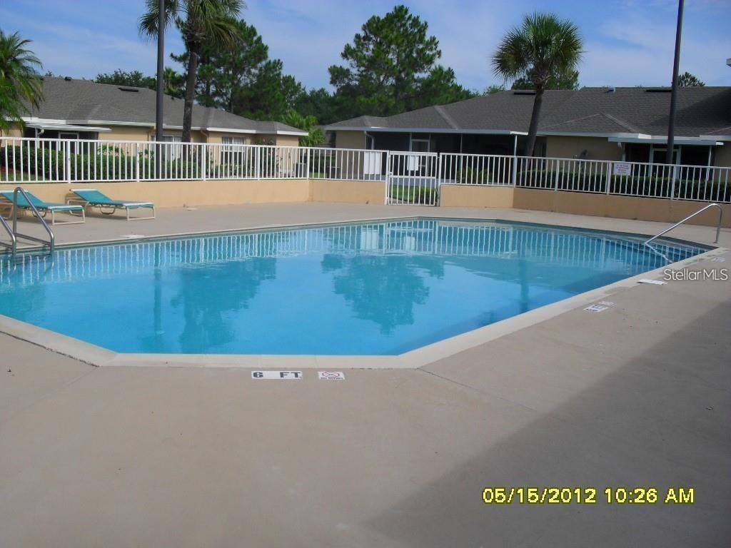 A swimming pool with a white fence is surrounded by a concrete deck and buildings — 1225 GARDEN ISLE COURT, ORLANDO, FL
