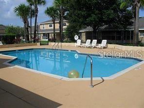 An outdoor swimming pool with lounge chairs on a concrete deck surrounded by palm trees — 1225 GARDEN ISLE COURT, ORLANDO, FL