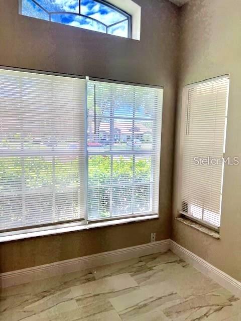 A room with marble-look tile flooring, large windows with blinds, and a high arched transom window — 1225 GARDEN ISLE COURT, ORLANDO, FL