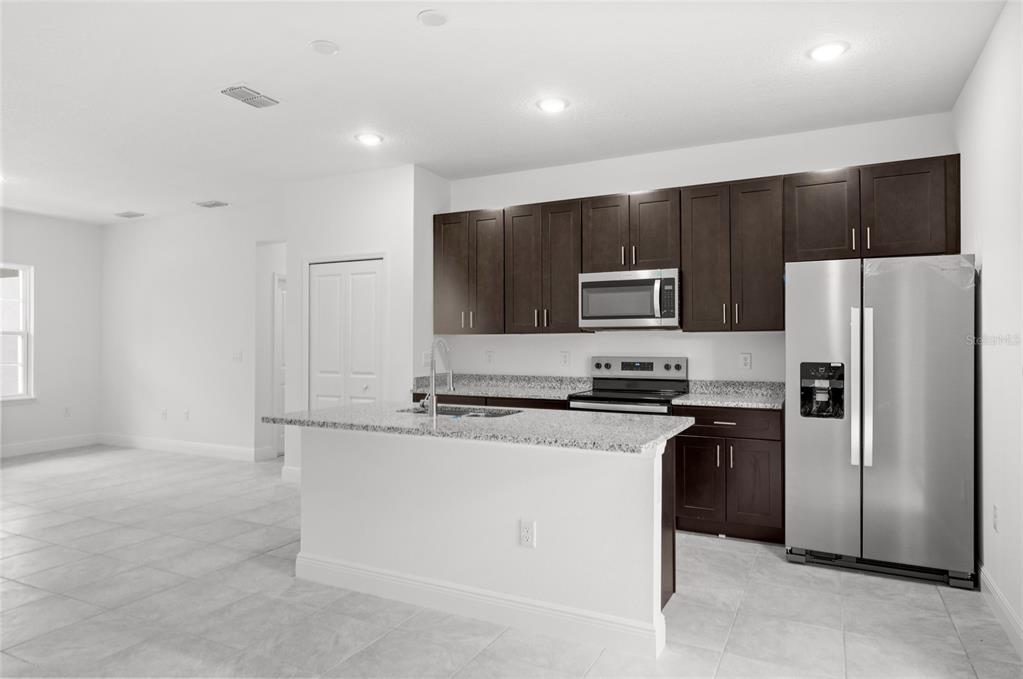 A kitchen with dark wood cabinets, granite countertops, and stainless steel appliances in an open space — 3179 W BARBERTON PLACE, CITRUS SPRINGS, FL