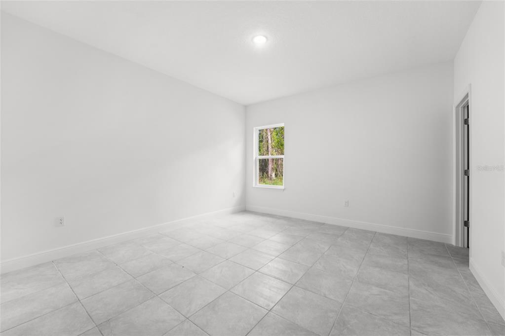 An empty room with white walls, light gray tile flooring, and a single window — 3179 W BARBERTON PLACE, CITRUS SPRINGS, FL
