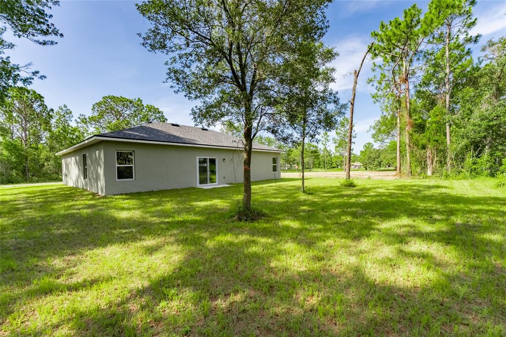 The exterior of a single-story house with a gray stucco finish and a grassy yard — 3179 W BARBERTON PLACE, CITRUS SPRINGS, FL