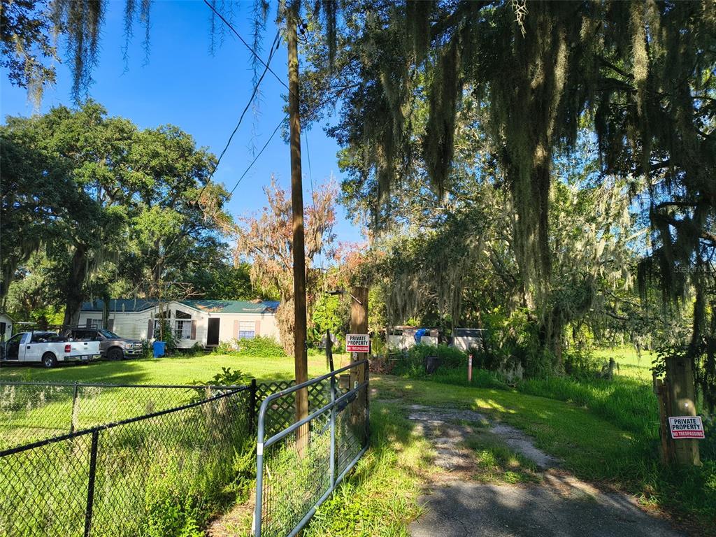 A gated gravel driveway leads to a mobile home surrounded by trees with hanging moss — 3609 MAXWELL ROAD, PLANT CITY, FL