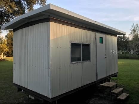 A small, rectangular, white metal shed with a single window sits on a grassy lot — 2406 SE 36TH STREET, GAINESVILLE, FL