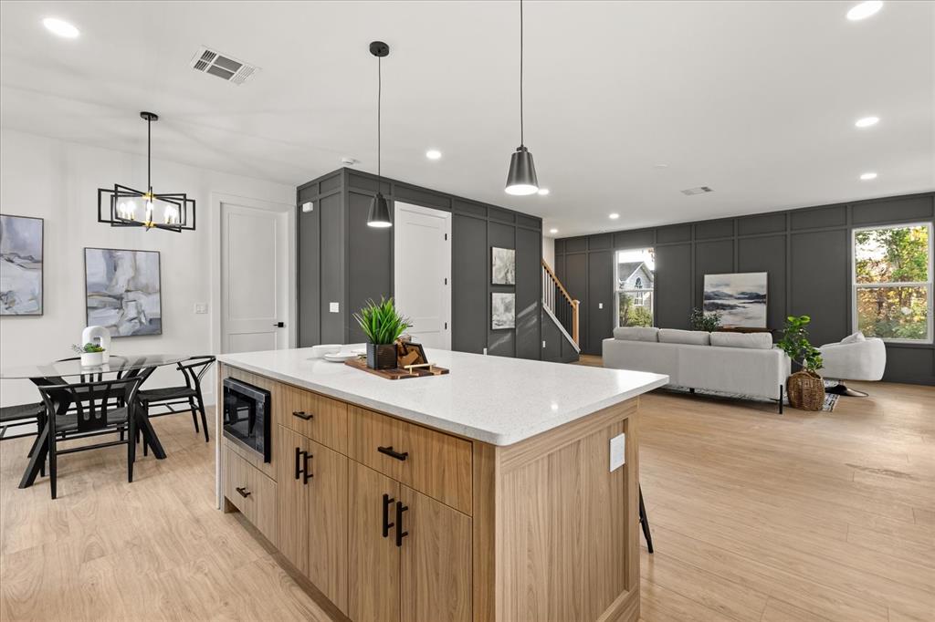 A kitchen island with wood cabinets and a white countertop sits before a living area — 1315 E HARDING STREET, ORLANDO, FL
