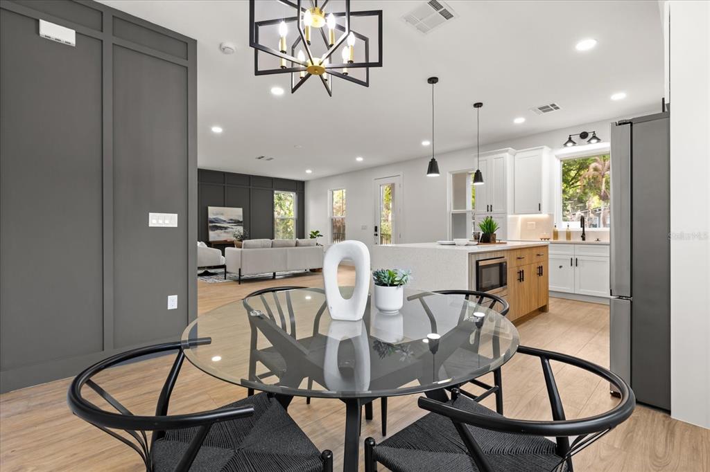 A dining area with a glass table and black chairs overlooks an open-concept kitchen — 1315 E HARDING STREET, ORLANDO, FL