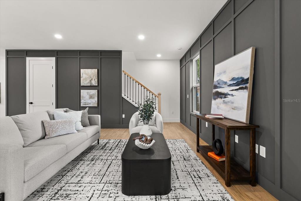 A living room features dark gray paneled walls, a light gray sofa, and a staircase — 1315 E HARDING STREET, ORLANDO, FL