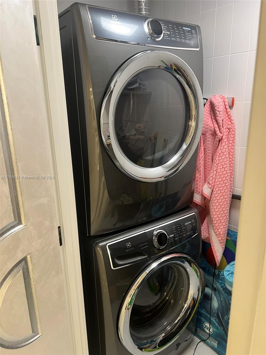 A stacked Electrolux washer and dryer set is installed in a small tiled laundry closet — 9801 W Collins Ave, Bal Harbour FL 33154, BAL HARBOUR, FL