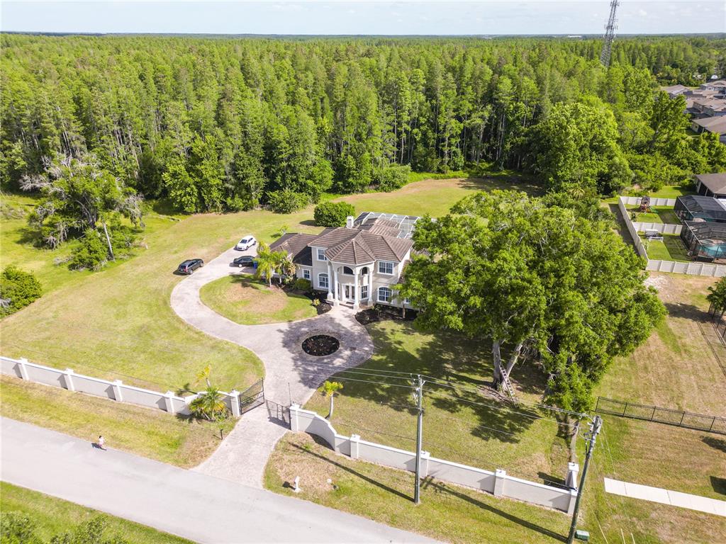 An aerial view shows a large two-story house with a pool enclosure and gated driveway — 19153 GERACI ROAD, LUTZ, FL