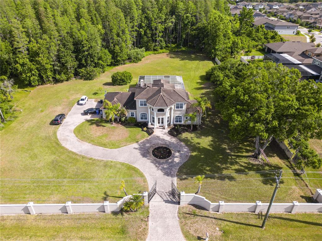 An aerial view shows a large two-story house with a circular driveway and gated entrance — 19153 GERACI ROAD, LUTZ, FL