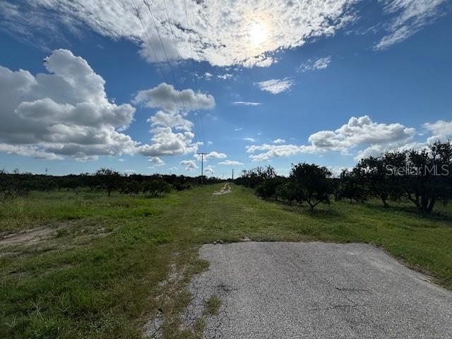 A paved driveway leads into a grassy field lined with trees under a cloudy sky — BAGLEY ROAD, HAINES CITY, FL