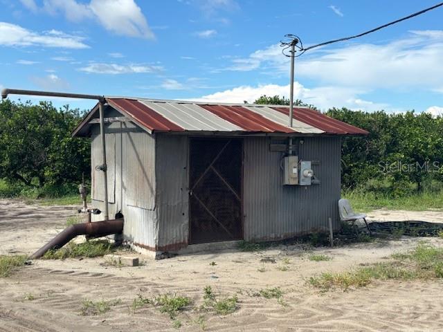 A small, corrugated metal shed with a rusted roof sits in a field — BAGLEY ROAD, HAINES CITY, FL