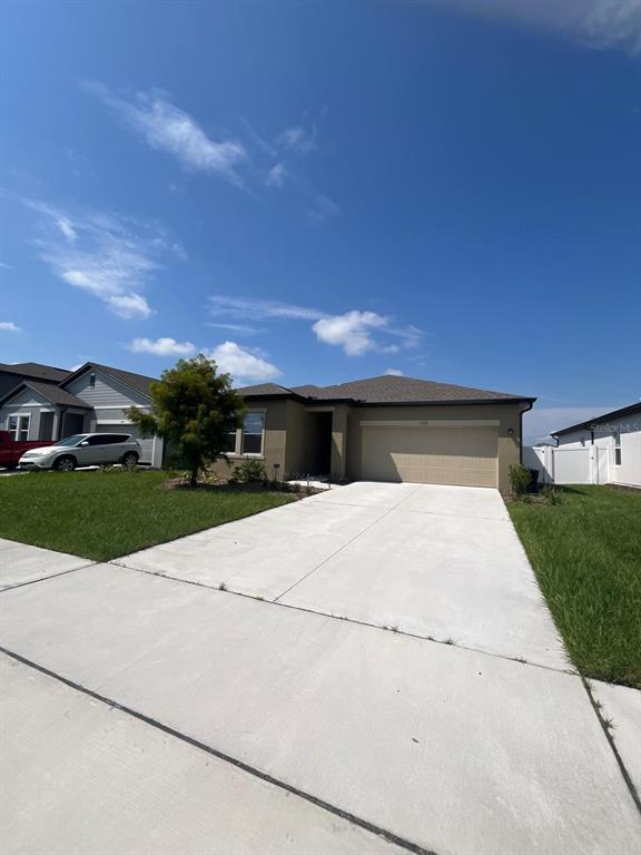 A single-story house with a tan exterior, a two-car garage, and a concrete driveway — 1332 DALKEITH COVE, SANFORD, FL