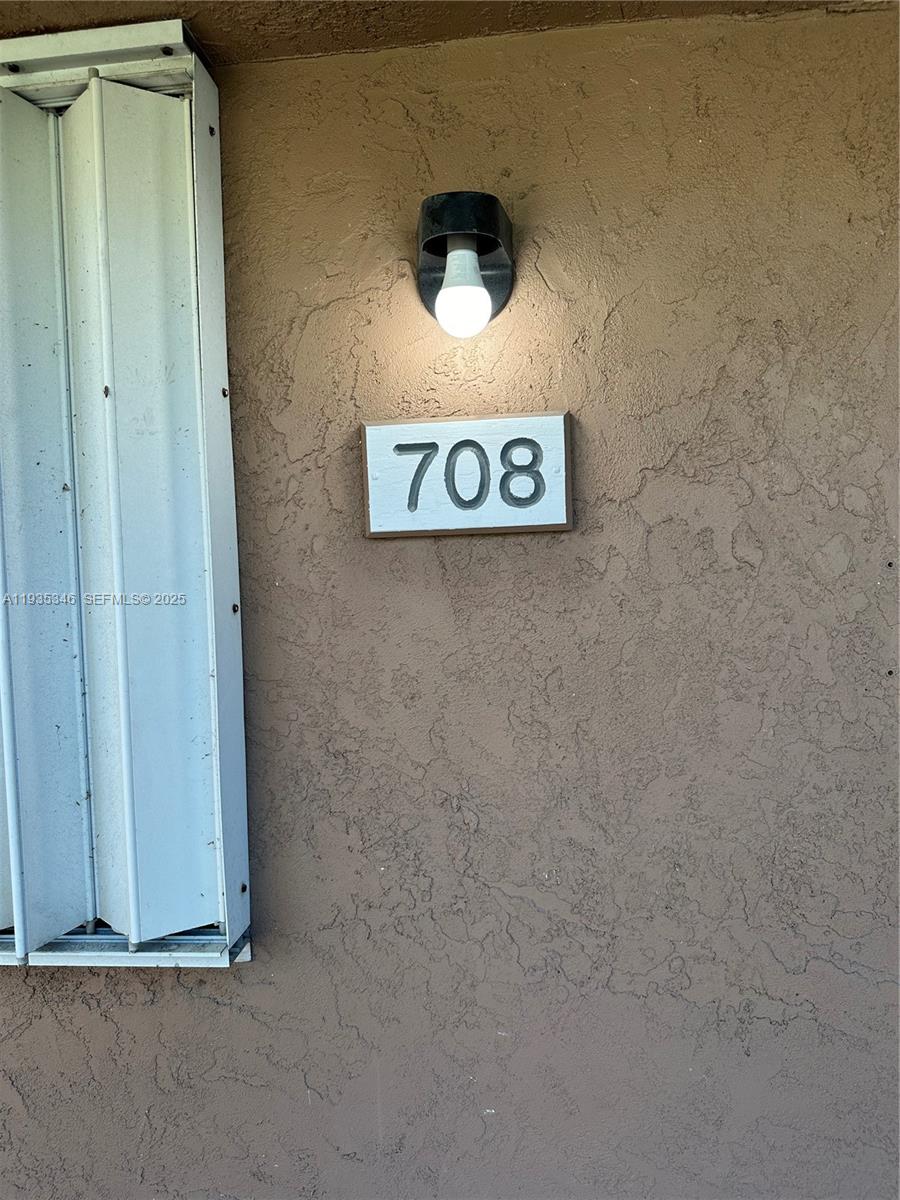A light fixture is mounted above a house number sign on a textured brown wall — 708 SE 3rd Ave Ext # 201, Hallandale Beach FL 33009, HALLANDALE BEACH, FL