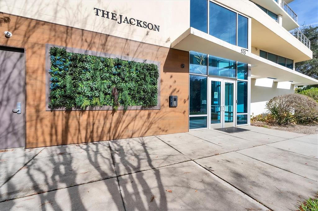 The exterior entrance of a modern building features a vertical garden and glass doors — 525 E JACKSON STREET UNIT 301, ORLANDO, FL