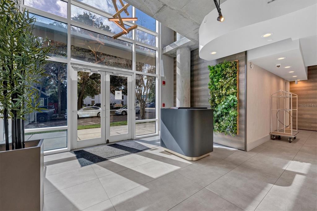 A modern building lobby features a reception desk, a vertical garden, and floor-to-ceiling glass doors — 525 E JACKSON STREET UNIT 301, ORLANDO, FL