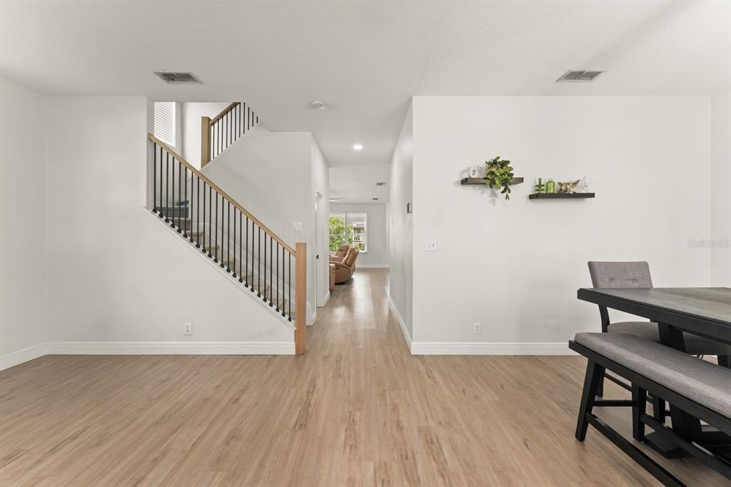 A dining area with wood-look flooring features a staircase and a view into a living room — 611 BROOKFIELD TERRACE, DELAND, FL