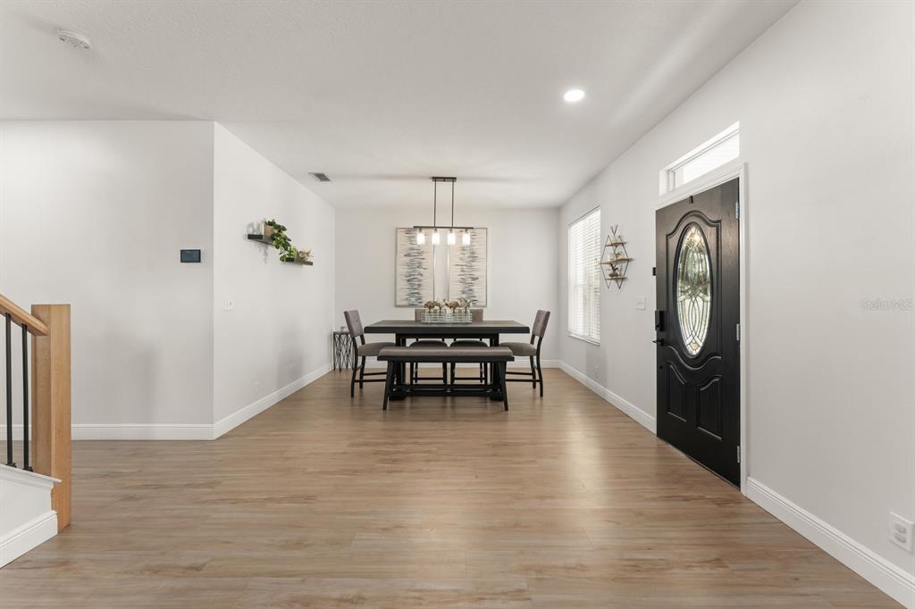 A dining area with wood-look flooring, a dark table, and a black front door — 611 BROOKFIELD TERRACE, DELAND, FL