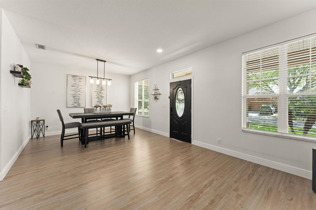 A dining area with light wood-look flooring, a black table set, and a front door — 611 BROOKFIELD TERRACE, DELAND, FL